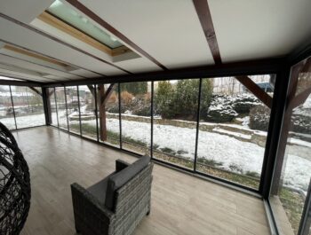 Detailní pohled na montáž zasklení na pomocné hliníkové profily řešící vnitřní vzpěry dřevěné konstrukce pergoly.