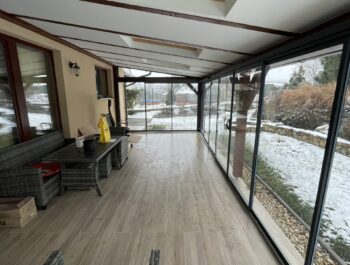 Posuvný systém rámového zasklení s bezpečnostním kaleným sklem a povrchovou úpravou komaxit v odstínu RAL 7016.