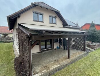 Rekonstrukce střechy pergoly: výměna polykarbonátu za čiré bezpečnostní sklo Connex v hnědých profilech RAL 8017.