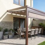 Detailní pohled na hnědou hliníkovou pergolu s baldachýnem a zataženou čelní screenovou roletou, která věrně napodobuje vzhled dřevěné pergoly 6X4.
