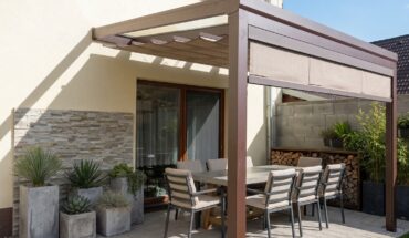 Detailní pohled na hnědou hliníkovou pergolu s baldachýnem a zataženou čelní screenovou roletou, která věrně napodobuje vzhled dřevěné pergoly 6X4.